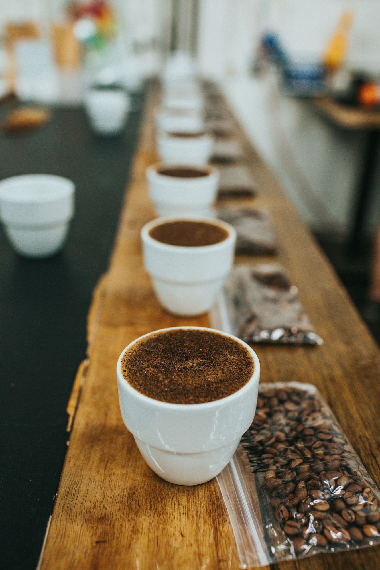 Row of cupping bowls with ground coffee set up for a quality tasting