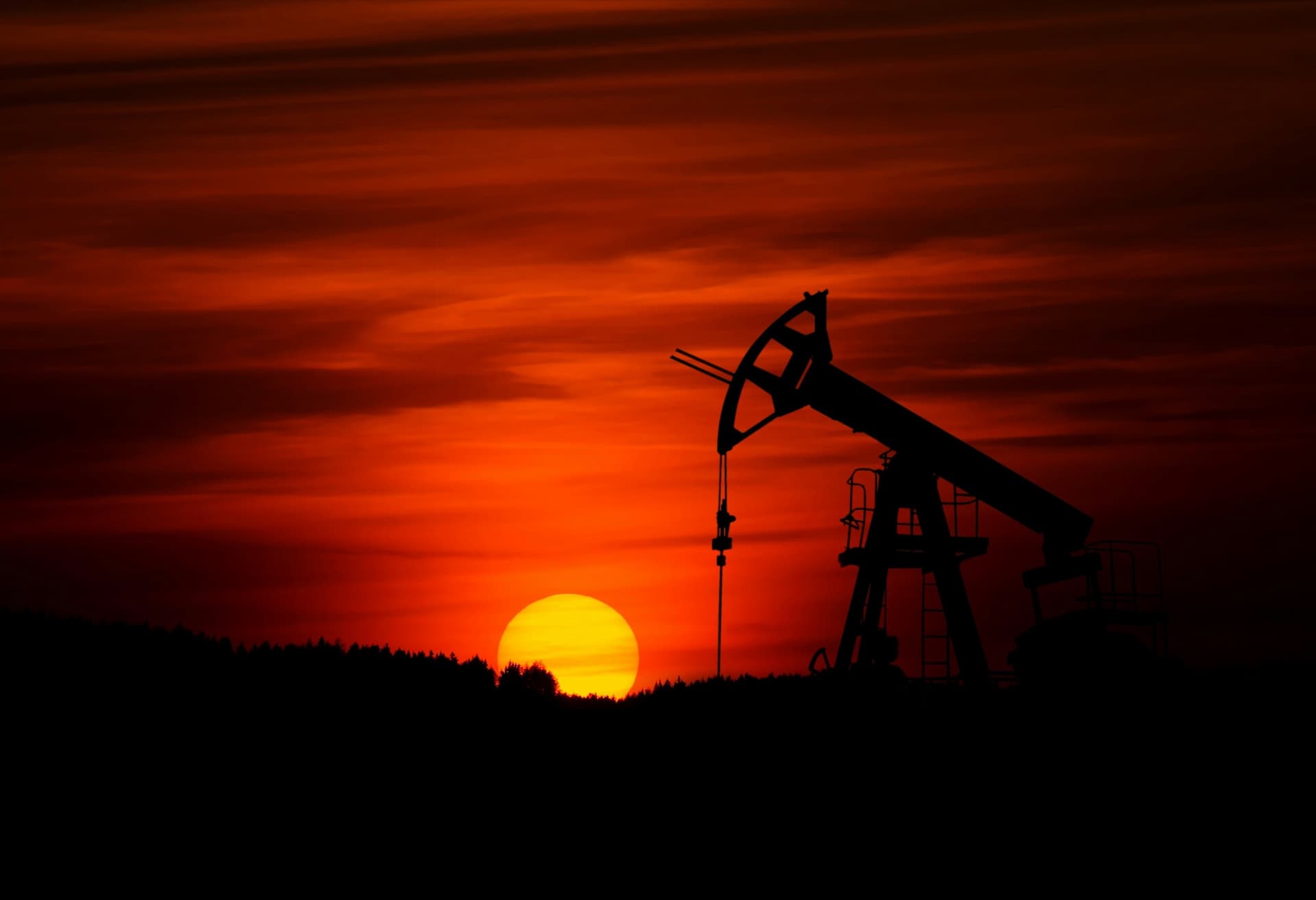 Oil pump jack silhouetted against a sunset sky